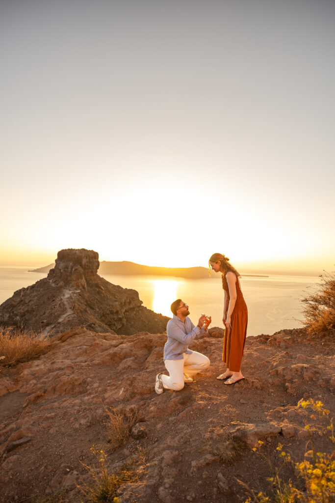 Man on knees in Santorini propose with sunset background